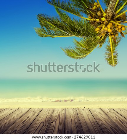 Vintage effect (retro style). Empty wooden table, coconut palm tree, ocean and blurry  beach. Tropic island background.