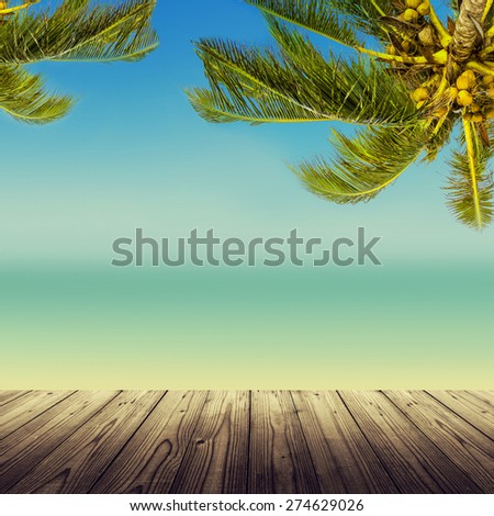 Vintage effect (retro style). Empty wooden table, coconut palm tree, ocean and sandy beach. Tropic island background.