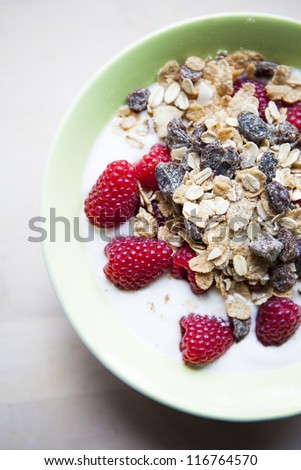 Bowl with sour milk, musli and raspberries.