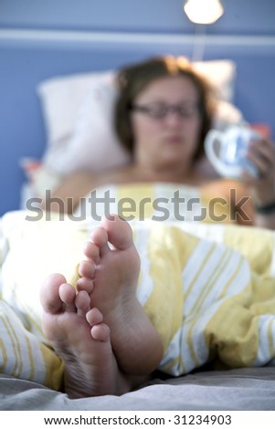 Woman in bed, feet in front. Shallow focus