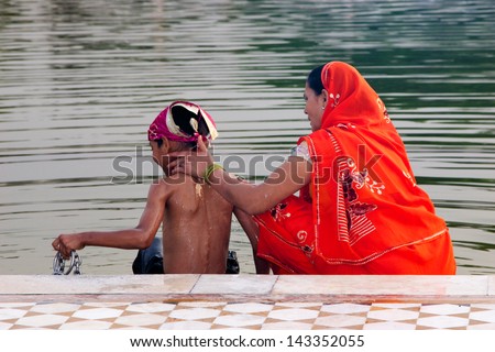 DELHI, INDIA - APRIL 22 : A mother gives her son a wash in sacred water at Gurudwara Bangla Sahib, a Sikh Temple in Delhi on 22 April, 2013.