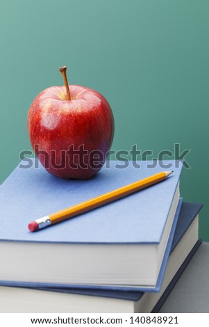 Green Chalkboard, Books and Apple in Classroom Setting with Copy Space.
