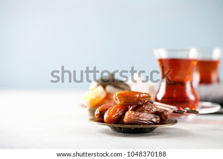 Eid mubarak with  tea and dates. Dried dates and red tea in the Arab glasses on a dark background. Ramadan, Eid concept. Copy space