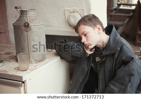 the boy stays at home at a table in ruins of the old