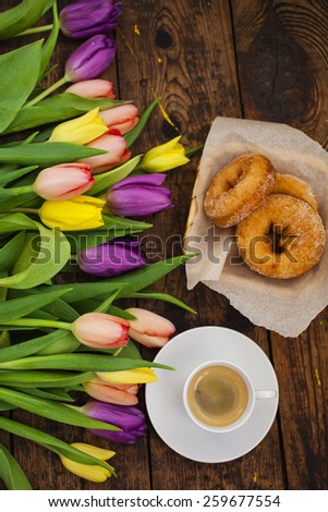 bouquet of tulips, coffee and donuts on a table, selective focus