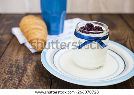 yogurt in a jar, croissant and coffee on a table, selective focus