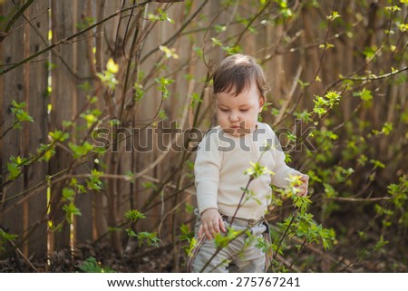 the little girl stands in bushes near a fence, selective focus