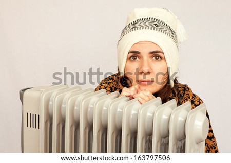 Freezing young woman near a heater