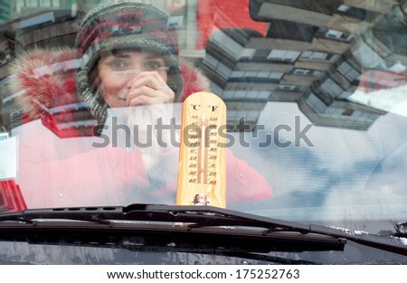 Girl inside the car with a thermometer on the wind screen