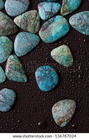 Texture of polished wet turquoise gemstones on the black background.