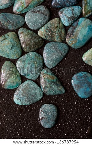Wet blue turquoise gemstones on the black surface.