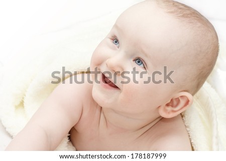 toddler with blue eyes looking out from under blanket