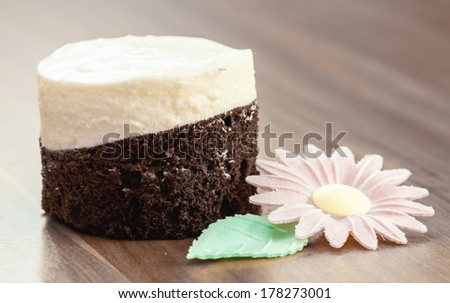 close up of piece of round cake on wood desk with flower