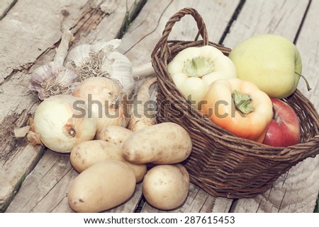 autumn vegetables with basket - apples, potatoes, onions, paprika and garlic