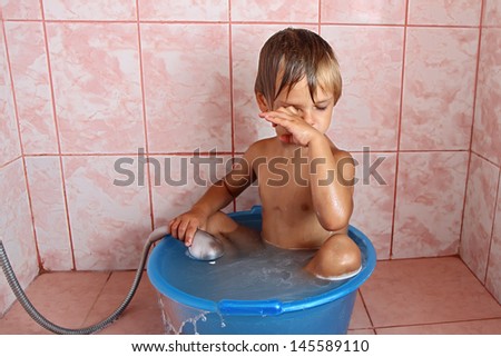 Cute boy washes his face in the shower.