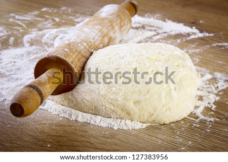 Dough with rolling pin on wooden table