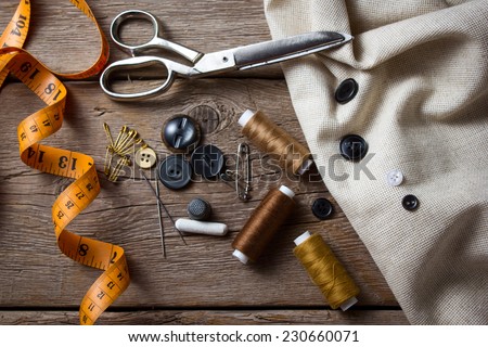 Sewing accessories: scissors, needle, thimble on wooden table