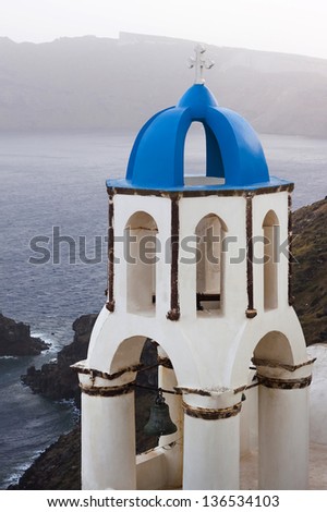Blue and white church\'s belltower with beautiful view of the sea at Oia village in Santorini island, Greece