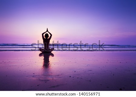 Woman practicing yoga on the beach at sunset in Koh Chang, Thailand