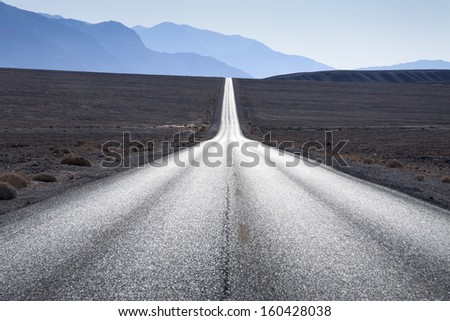 Straight Road Towards Mountain Range In Horizon At Death Valley, Usa