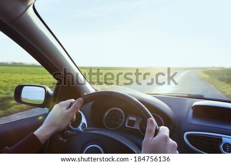 Person driving car with blue sky and green grass