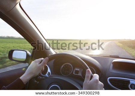 Hands of young driver on steering wheel during road trip with rental car