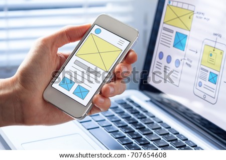 Mobile responsive website development with UI/UX front end designer previewing wireframe sketch layout design mockup on smartphone screen