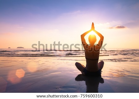 Yoga and meditation on the calm peaceful beach at sunset, fit young woman