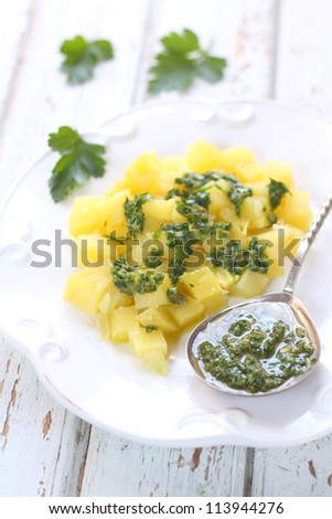 potato salad with green sauce on a white plate