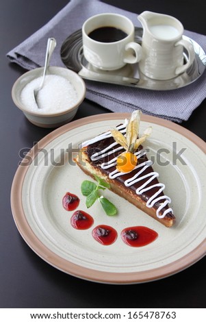 slice of chocolate cake on a plate on the table with a cup of coffee and cream