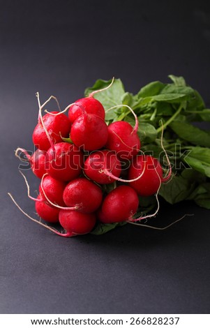 bunch of a red garden radish with green leaves in the black table