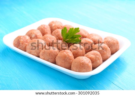 meat balls from raw minced meat in a white tray on a blue background