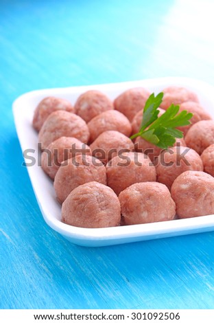 meat balls from raw minced meat in a white tray on a blue background