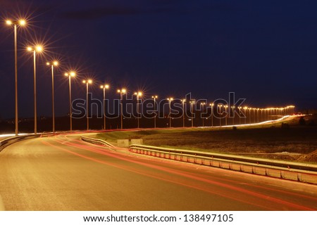 Lighting the night highway, road lighting masts, night view, horizontal photo.