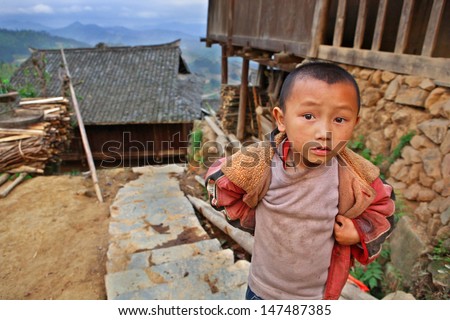 GUIZHOU PROVINCE; CHINA - APRIL 10: 7 years old boy near a wooden house in the village of ethnic minority Miao, April 10, 2010. Basha Miao Village, Congjiang County, Southeast Guizhou, Southwest China