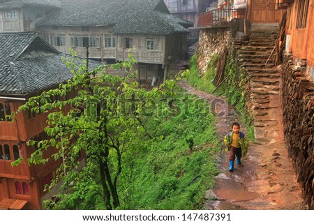 GUANGXI PROVINCE, CHINA - APRIL 4: A little boy goes through the village path, past the wooden buildings., April 4, 2010. Xiaozhai village, near Longsheng. Minority Yao people in area of Guilin city.