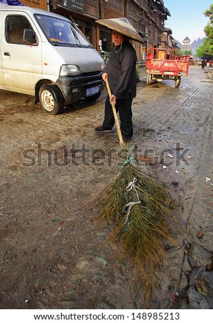 GUIZHOU PROVINCE, CHINA - APRIL 8: Chinese janitor sweeping the main street of the village of bamboo broom, April 8, 2010. Zhaoxing Dong ethnic minorities village, Liping County.