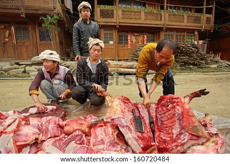 GUIZHOU PROVINCE, CHINA - APRIL 12: Chinese peasants, farmers, pork is cut on a rural road in Zengchong village, province of Guizhou, April 12, 2010. Chinese farmer livestock, pigs carcass of cuts ax.