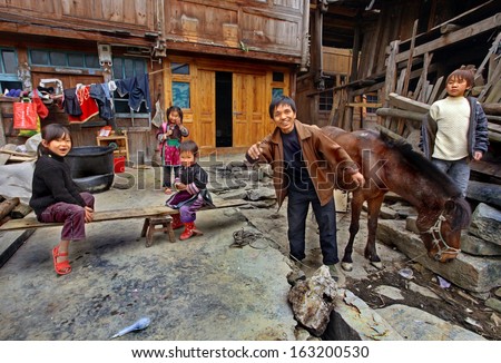 GUIZHOU PROVINCE, CHINA - APRIL 12: Asian family in the countryside of southwestern China, a father and his four children, and relax in front of his wooden house in the peasant economy, April 12, 2010