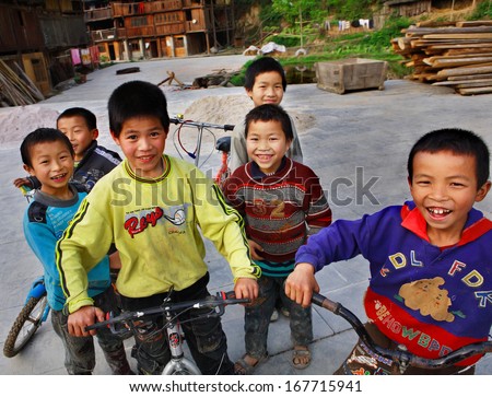 GUIZHOU, CHINA - APRIL 8: East Asia, the Chinese rural children laughing, smiling and riding bikes in the Zhaoxing Dong Village, Guizhou Province, China - April 8, 2010.