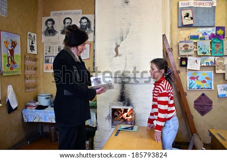 Tver, Russia - May 2, 2006: School teacher gives a lesson schoolgirl pupil, Schegoleva Tanya, 11 years old,  in a school class room, next to a stone oven for wood heating, with burning firewood.