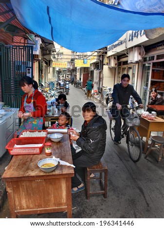 SHANGHAI, CHINA  -  APRIL 20, 2010: Street eatery in a poor area, Chinese lunch with a child outdoor.