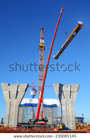 St. Petersburg, Russia - October 29, 2014:  Counter Jib Is Installed. Red mobile crane lifts a section of yellow tower crane on background of blue sky in sunny weather, installation, assembly of crane