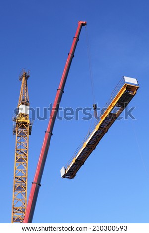 Crane erection process, setting up a tower crane.  Tower Mast Is Being Built With The Mobile Crane. Assembling tower crane using a mobile crane.