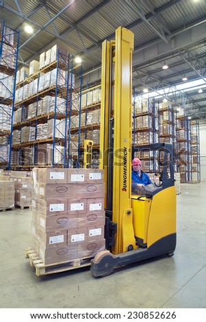 St. Petersburg, Russia - November 21, 2008: The driver of a yellow forklift truck operates, in warehouses, sitting in the workplace. A fork lift truck moves stacked pallets. Forklift palletiser.