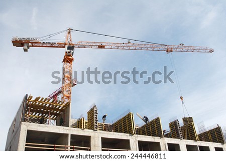 St. Petersburg, Russia - September 8, 2008: Construction site of residential building, monolithic construction, yellow tower crane lifts blocks, workers stand on the walls of an unfinished house.
