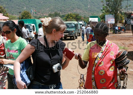 Namanga, Tanzania - February 9, 2008: Border checkpoint on the border of Kenya and Tanzania, the Masai tribe woman trying to sell bracelets to tourists from Europe.
