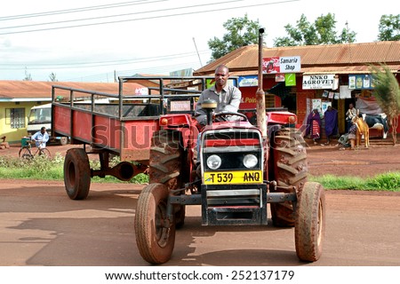 Makuyuni, Arusha, Tanzania - February 13, 2008: African, Tanzanian farmer tractor driver, sitting behind the wheel of a agrimotor without a cab, with bodywork trailer.