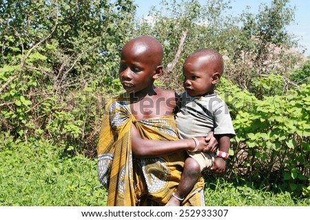 Meserani Snake Park, Arusha, Tanzania - February 14, 2008: Two unknown black children Maasai elder brother about 8 years old, holds a younger brother or sister, about 2 years old.
