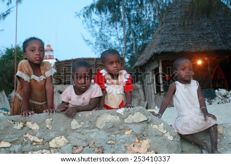 Zanzibar, Tanzania - February 19, 2008: Fishing village, four unidentified small black African Arabian girl, the approximate age of 4-6 years, resting on a stone fence in the evening, after sunset.